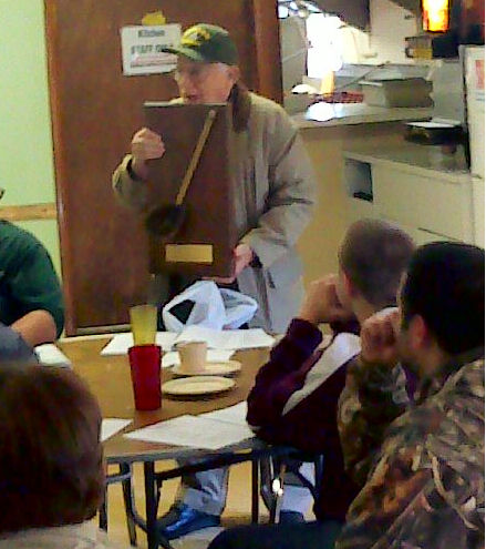 Buddy holds up a plaque with scrub brush mounted on it